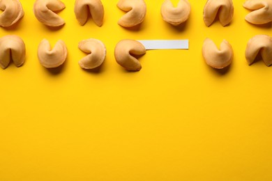 Photo of Many tasty fortune cookies with predictions on yellow background, flat lay. Space for text
