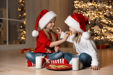 Cute little children eating cookies in living room. Christmas time