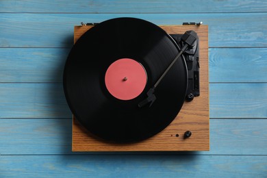 Modern vinyl record player with disc on blue wooden background, top view