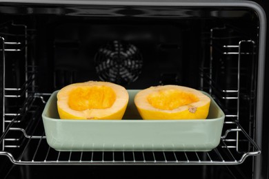 Baking dish with halves of fresh spaghetti squash in oven