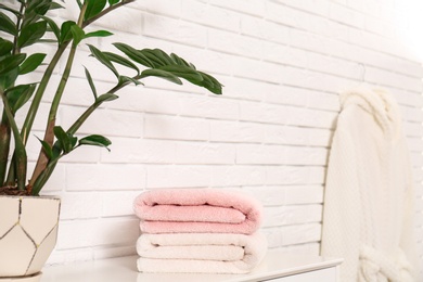 Clean folded towels on table near brick wall. Space for text