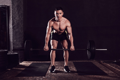 Strong man lifting barbell in modern gym