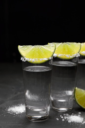 Mexican Tequila shots, lime slices and salt on black table