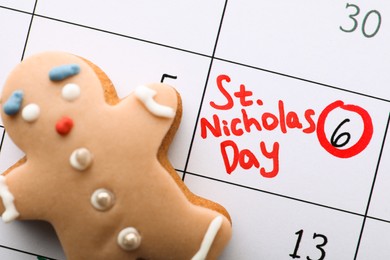 Gingerbread cookie on calendar page with marked date, top view. December, 6 - Saint Nicholas Day