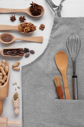 Photo of Flat lay composition with grey apron, ingredients and kitchen utensils on white table