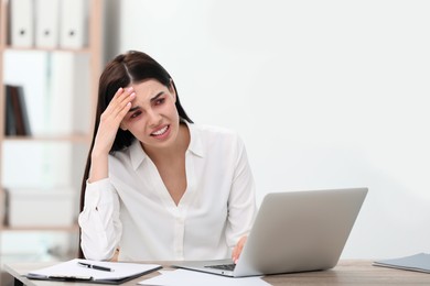 Tired woman with red eyes at workplace in office