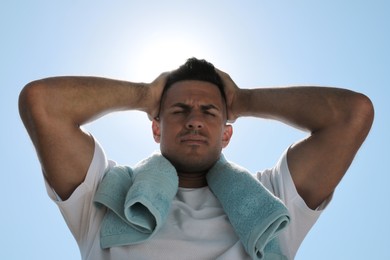 Man with towel suffering from heat stroke outdoors, low angle view