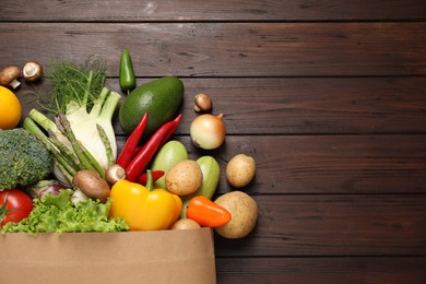 Photo of Fresh vegetables in paper shopping bag on wooden table, flat lay. Space for text