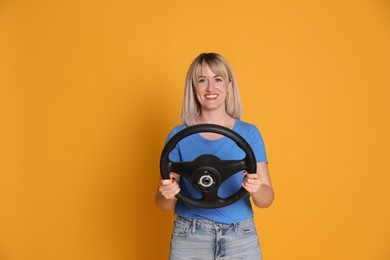 Happy woman with steering wheel on yellow background. Space for text