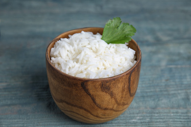 Bowl with tasty cooked rice on light blue wooden table, closeup