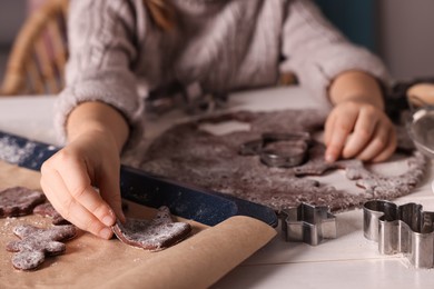 Little child making Christmas cookies at white wooden table, closeup
