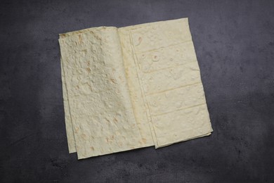 Photo of Delicious folded Armenian lavash on dark table, top view
