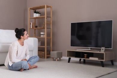 Woman watching television at home. Living room interior with TV on stand