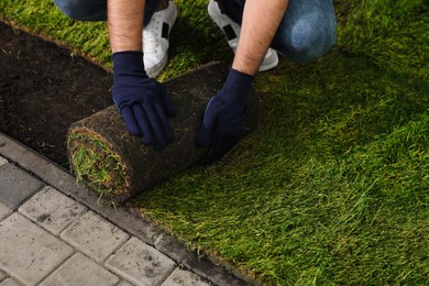 Young man laying grass sod on ground in garden, closeup