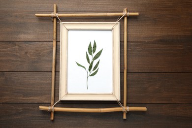 Bamboo frame with dried plant on wooden table, top view
