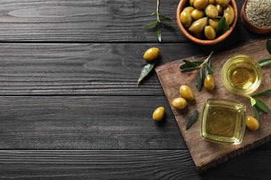 Flat lay composition with olive oil on black wooden table. Space for text
