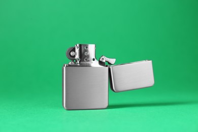 Photo of Gray metallic cigarette lighter on green background, closeup