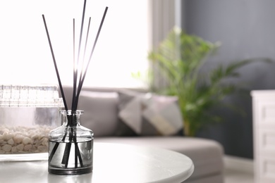 Photo of Aromatic reed air freshener on white table in room. Space for text