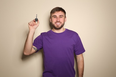 Happy young man with car key on color background. Getting driving license