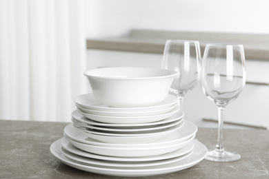 Stack of clean plates and glasses on marble table in kitchen