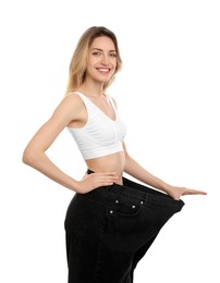 Young woman wearing big jeans after weight loss on white background