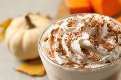 Delicious pumpkin latte with whipped cream on table, closeup
