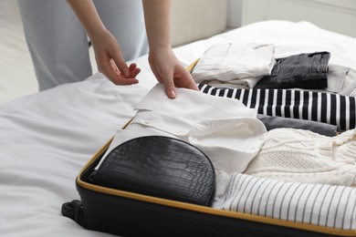 Woman packing suitcase for trip in bedroom, closeup