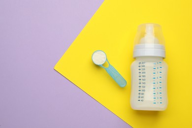 Feeding bottle with infant formula and powder on color background, flat lay. Space for text