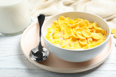 Photo of Tasty corn flakes with milk on white wooden table