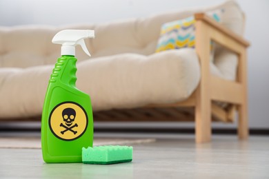 Photo of Bottle of toxic household chemical with warning sign and scouring sponge in room, space for text