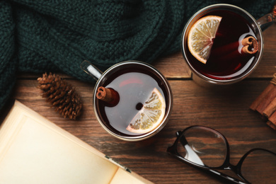 Glass cups of delicious mulled wine on wooden table, flat lay. Winter drink