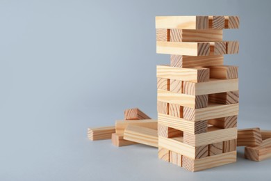 Jenga tower made of wooden blocks on grey background, space for text