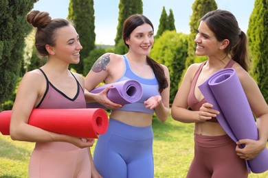 Young women in sportswear with yoga mats talking outdoors