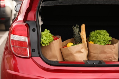 Bags full of groceries in car trunk outdoors, closeup
