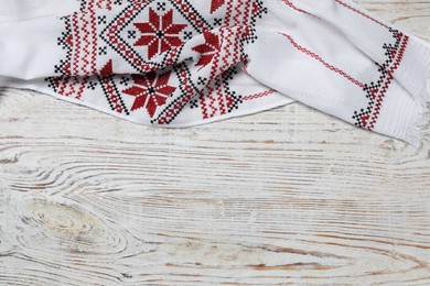 Beautiful rushnyk on white wooden table, top view with space for text. Ukrainian national embroidery