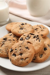 Plate with delicious chocolate chip cookies on white wooden table, closeup