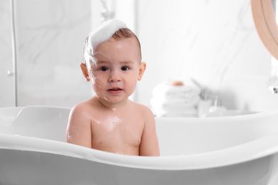 Cute little baby in bathtub at home