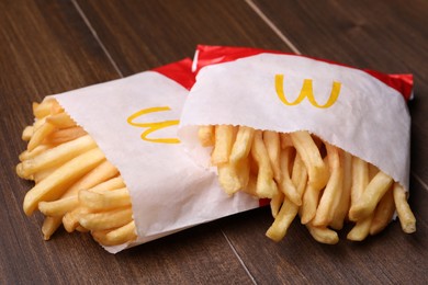 MYKOLAIV, UKRAINE - AUGUST 12, 2021: Two small portions of McDonald's French fries on wooden table, closeup