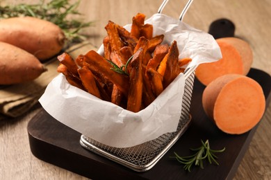 Frying basket with sweet potato fries on table, closeup
