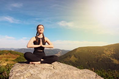 Young woman practicing yoga in mountains on sunny morning