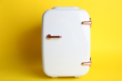 Mini refrigerator for cosmetics on yellow background