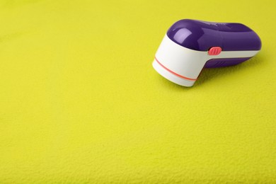 Photo of Fabric shaver on light green cloth with lint. Space for text