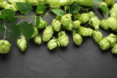 Photo of Fresh green hops and leaves on black table, above view. Space for text