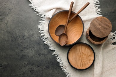 Stylish wooden dishware and spoons on grey table, flat lay. Space for text