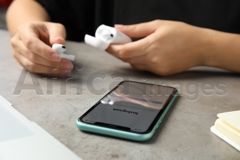 Photo of MYKOLAIV, UKRAINE - JULY 9, 2020: Woman using Iphone 11 with Instagram app on screen at table, closeup