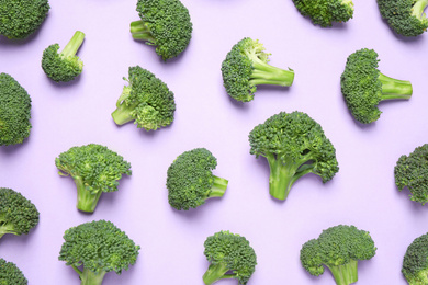 Fresh tasty broccoli on violet background, flat lay