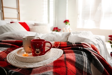 Christmas cups in tray on red woolen blanket. Bedroom interior