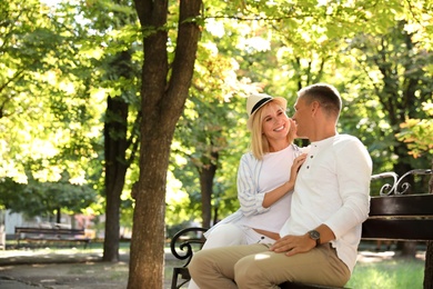 Happy couple sitting on bench in summer park