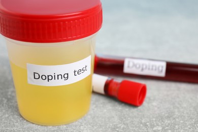 Jar of urine with words Doping test on light grey stone table, closeup. Space for text