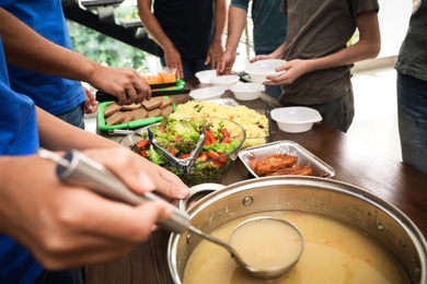 Volunteers serving food to poor people in charity centre, closeup